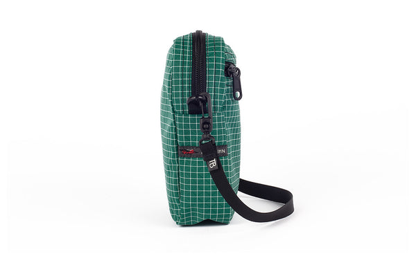 A side view of the Everyday Cubelet in Sitka Halcyon (green with a white grid) showing the o-ring attachment point and included 5/8" strap.